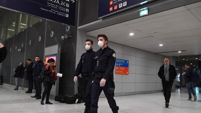 Policemen wearing protection masks patrol the arrival Terminal of Charles De Gaulle Airport in France. The virus has spread outside Asia and also harmed financial markets. AFP