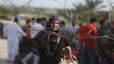 A Palestinian woman stands by a fence as she waits for a travel permit to cross into Egypt through the Rafah border crossing after it was opened by Egyptian authorities for humanitarian cases, in Rafah in the southern Gaza Strip August 16, 2017. Ibraheem Abu Mustafa / Reuters