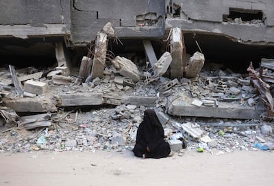 A Palestinian woman sits in front of what is left of a building following Israeli military strikes in Khan Yunis. AFP