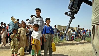 A US soldier stands guard in front of Iraqi children waiting to get petrol in Fallujah. EPA.