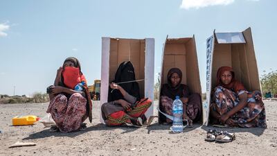 Refugees shelter from the sun in UNHCR-branded cardboard boxes as they wait to be registered in the grounds of a closed hotel, in Semera, Afar region, Ethiopia. AFP