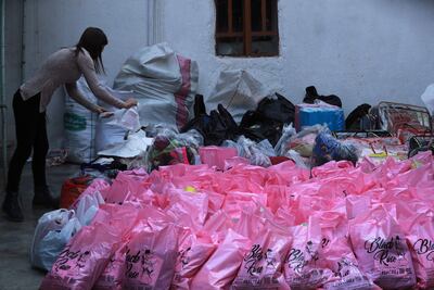 A Syrian Kurdish woman collects clothes and food in the northeastern city of Qamishli on December 7, 2024, to distribute to Kurds displaced from towns in the Aleppo countryside. AFP