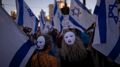 Demonstrators in Tel Aviv wear masks and wave Israeli flags during a protest against plans by Prime Minister Benjamin Netanyahu's government to change the country's judicial system. AP