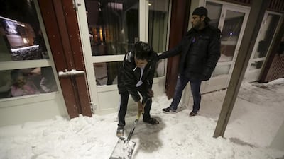 A refugee clears snow at the entrance of a camp at a hotel touted as the world’s most northerly ski resort in Riksgransen, Sweden. Ints Kalnins / Reuters