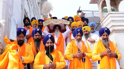 A Sikh priest (C), carries the Sri Guru Granth Sahib ji, the holy book of Sikh religion, on his head during a procession at the Golden Temple in Amritsar, India. EPA
