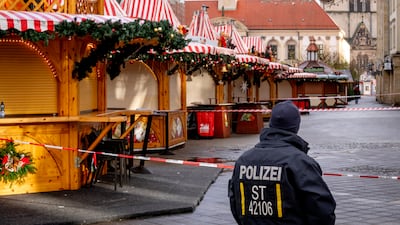A German police officer stands guard at the Magdeburg Christmas market, where a car was driven into a crowd on Friday evening. There are suggestions that Saudi warnings about the suspect went largely unheeded by their German counterparts. AP