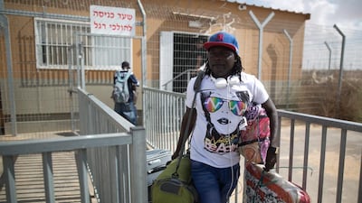 An African asylum seeker carries belongings following his release from the Holot Detention Centre in Israel's Negev desert on August 25, 2015. Menahem Kahana / AFP