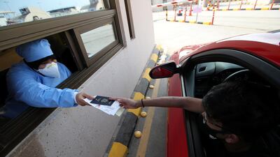A medical inspector hands documents back to a motorist before entering Bahrain. Reuters