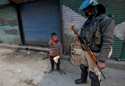 A boy plays with his toy pistol next to an Indian policeman standing guard in front of closed shops during a strike called by Kashmiri separatists against the arrest of Yasin Malik, Chairman of Jammu Kashmir Liberation Front (JKLF), a separatist party, in Srinagar March 8, 2019. Photo: Reuters