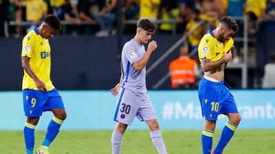 Cadiz's Alberto Perea, right, and his teammate Anthony Lozano, left, walk off the pitch with Barcelona's Gavi Paez. AP