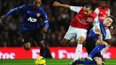 Theo Walcott of Arsenal splits Manchester United players Patrice Evra, left, and Michael Carrick.