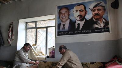 Kheder Pakdaman, right, one of the KDPI's senior Peshmerga commanders, relaxes with a game of Backgammon while party luminaries watch on. (Florian Neuhof for The National)