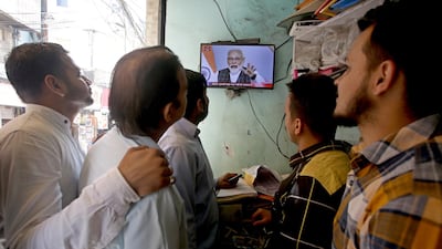 Indians watch Prime Minister Narendra Modi's televised address to the nation, at a shop in Jammu. EPA