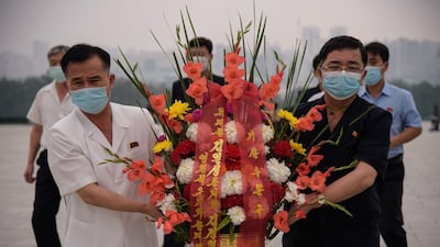 People carry a floral bouquet as they prepare to pay their respects before the statues of late North Korean leaders Kim Il Sung and Kim Jong Il at Mansu hill in Pyongyang. AFP