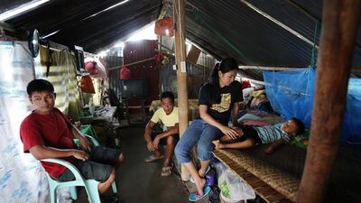 Aiza Tonida beside her son Jaizen Jericho Caga, two, with husband Jericho Caga and her father Gualberto Tonido inside their temporary shelter. (Joey Reyna for The National / April 9, 2014)