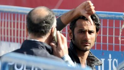 A man flashes a thumbs down gesture as he is escorted by Turkish police upon the arrival of migrants by ferry from the Greek island of Lesbos at the Dikili harbour in Izmir, Turkey. Tolga Bozoglu / EPA