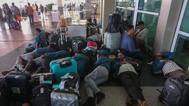 Passengers rest outside Terminal 1 of New Delhi's Indira Gandhi International Airport after mass cancellation of Indigo flights on December 5, 2025. Getty Images