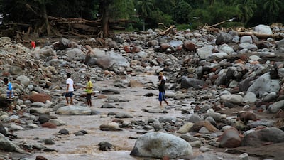 Residents walk on boulders swept by flashfloods in a village in Salvador, Lanao del Norte in southern Philippines . Richel V. Umel / Reuters
