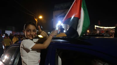 A child holds the Palestinian flag as people celebrate a ceasefire brokered by Egypt between Israel and the two main Palestinian armed groups in Gaza. AFP