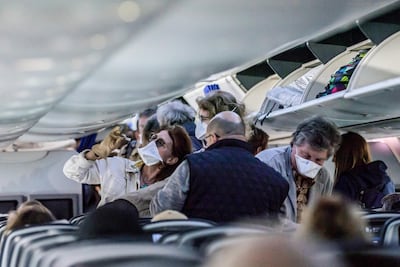 Passengers, some wearing protective face masks, aboard an EgyptAir flight bound for Cairo stow away their luggage in the overhead compartments prior to take-off from Luxor International Airport in southern Egypt. AFP
