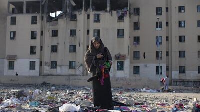 Omanius Shabaki tries to collect some of her family's belongings near her apartment building in the Sheikh Zayed City neighbourhood of Gaza. Their clothes were spread all over the street from the explosion. Heidi Levine for The National