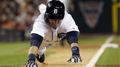 Detroit Tigers’ Andrew Romine dives home to score against the Chicago White Sox. Carlos Osorio / AP Photo