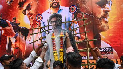 Fans spray milk on a banner displaying the picture of Indian actor Rajinikanth before the screening of his new Tamil-language movie 'Jailer' on the first day of its release, outside a theatre in Mumbai on August 10, 2023. (Photo by Punit PARANJPE / AFP)