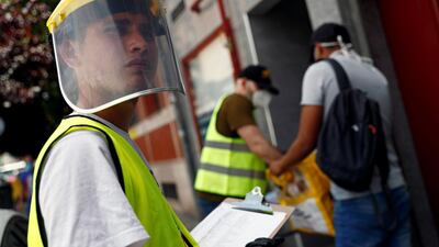 A volunteer wears a protective shield as a man receives donated food at San Ramon Nonato Catholic parish in Spain