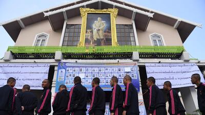 Voters wait in line under a portrait of Thailand's King Maha Vajiralongkorn to cast their ballots at a polling station in Bangkok. AFP