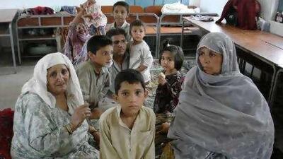 Chaman Gul, centre, and his extended family at the primary school camp.