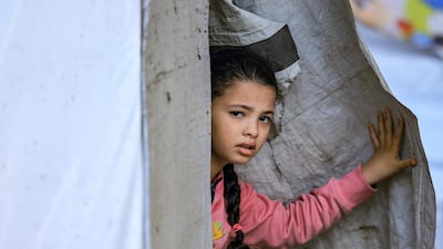 A young girl peeks through the entrance of a tent. AFP