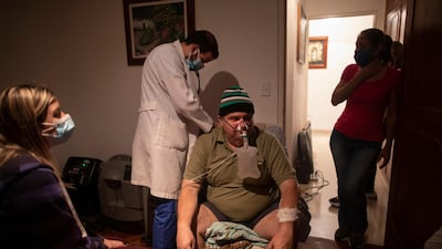 Doctor Leonardo Acosta, left, listens to the lungs of Carlos Perez, a Covid-19 patient, at his home in Caracas, Venezuela. AP Photo