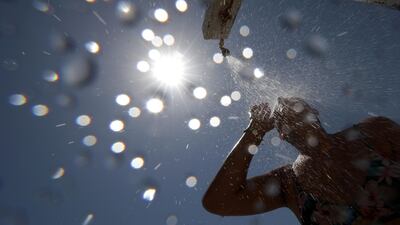 A woman stands under a shower on the beach in Nice as a heatwave hits much of the country. Reuters