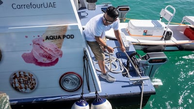 A Carrefour floating store crew member helps moor a yacht alongside. Antonie Robertson/The National