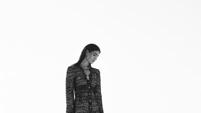 Black and gold tweed jacket; black and gold tweed skirt; necklace in metal and resin; and gold sandals in lamé leather, all from Chanel/