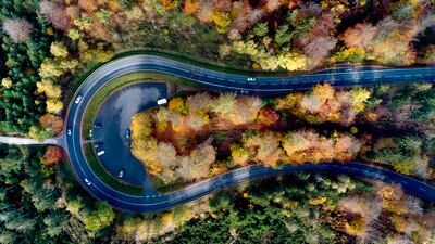 Cars drive around a curve in a forest in the Taurus region near Frankfurt, Germany. AP