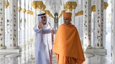 Sheikh Nahyan bin Mubarak and Mahant Swami Maharaj stand in the corridor of 1,096 pillars at the Sheikh Zayed Grand Mosque.