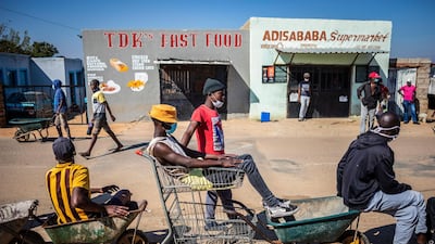 Wheelbarrow couriers wait to take food from a supply centre in Johannesburg to customers on day 40 of the South African lockdown. EPA