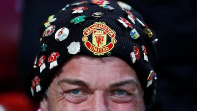AManchester United fan has plenty of badges on his hat. Action Images via Reuters