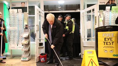 Boris Johnson helps with the clean up at an opticians in northern England. AFP