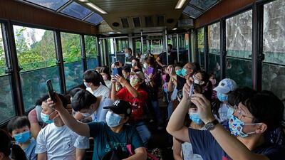 Passengers take photos from a Peak Tram during a tram journey in Hong Kong on June 17, 2021. Vincent Yu / AP Photo