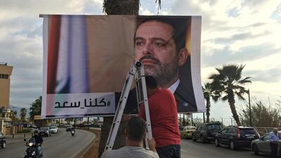 Workers hang a poster of outgoing Prime Minister Saad Hariri in Beirut, Lebanon on November 9,2017. The words in Arabic say, "We are all Saad." Hussein Malla / AP