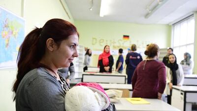 A woman holds a baby as she attends an orientation class for refugees in Berlin on November 11, 2016. Tobias Schwarz / AFP