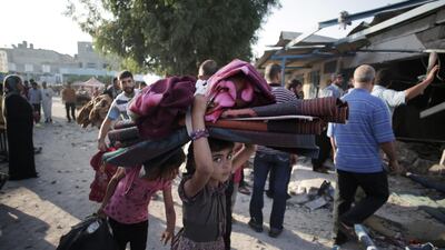 A Palestinian girl carries belongings as she and her family leave the Abu Hussein U.N. school in the Jebaliya refugee camp, northern Gaza Strip, hit by an Israeli strike. Khalil Hamra / AP Photo
