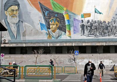 A man wearing a mask walks under a mural bearing an image of Iran's supreme leader Ayatollah Ali Khamenei in Tehran. AFP