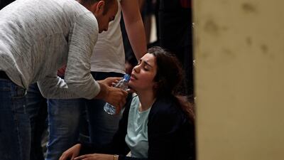 A man gives a drink of water to a woman grieving at the entrance of the morgue. AFP