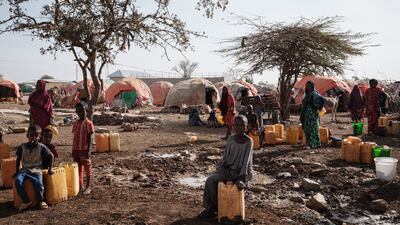 People wait for water with containers at a camp, in Baidoa.