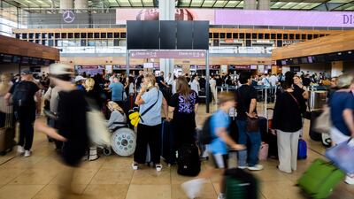 Numerous passengers wait in front of a black display board at the capital's Berlin Brandenburg Airport, in Schönefeld, Germany, Friday July 19, 2024. Air traffic has been suspended at BER Airport. A widespread Microsoft outage was disrupting flights, banks, media outlets and companies around the world on Friday. (Christoph Soeder / dpa via AP)
