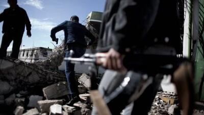 Armed Libya civilians walk over the debris of a destroyed army barrack in the eastern city of Benghazi.