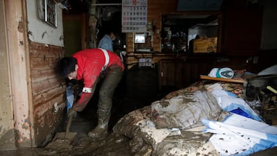Yoshiki Yoshimura, 17, cleans up mud at his home after Typhoon Hagibis passed through the neighborhood in Nagano, Japan. More victims and more damage have been found in typhoon-hit areas of central and northern Japan, where rescue crews are searching for people still missing. (AP Photo/Jae C. Hong)